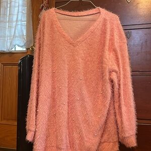 A pearled pink, fuzzy sweater with a low V-neck